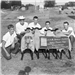 Five young men crouching down by sheep.