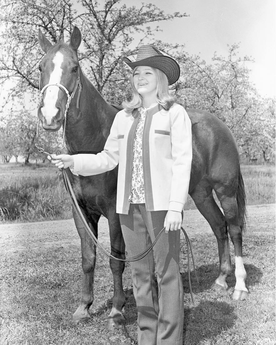 Young lady holding horse by reins.