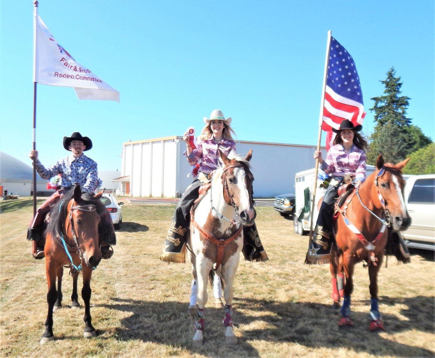 Fair Ambassadors riding horses holding flags and ribbon